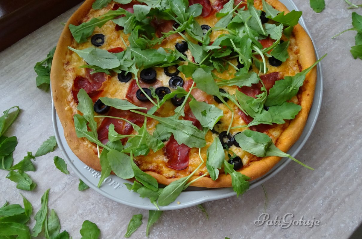 Pizza z szynką parmeńską oliwkami i rukolą